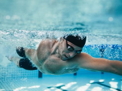 Underwater shot of fit swimmer training in the pool. Professional male swimmer inside swimming pool.